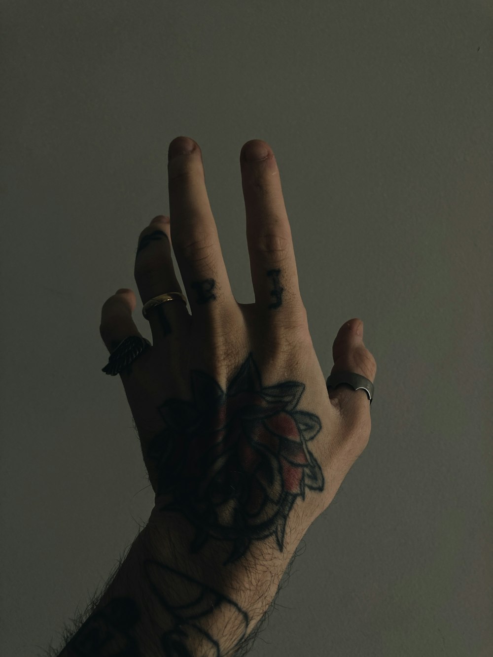 a hand with a tattoo holding up a ring