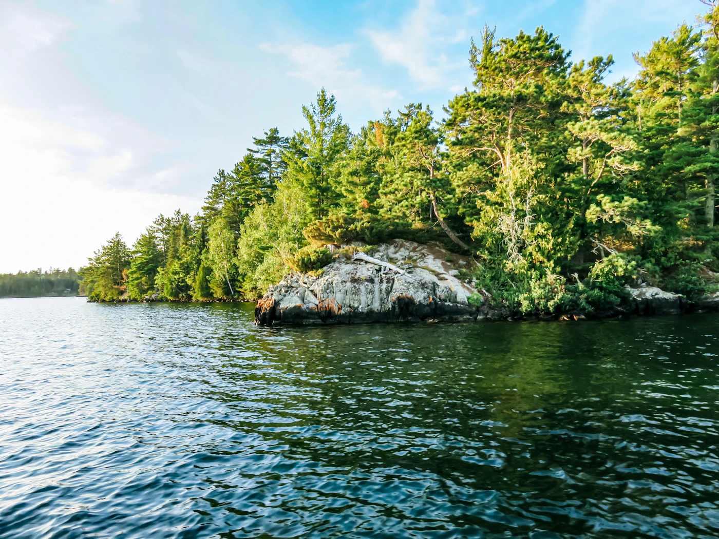 A tranquil morning at a remote Ontario lake with still water reflecting the surrounding forest