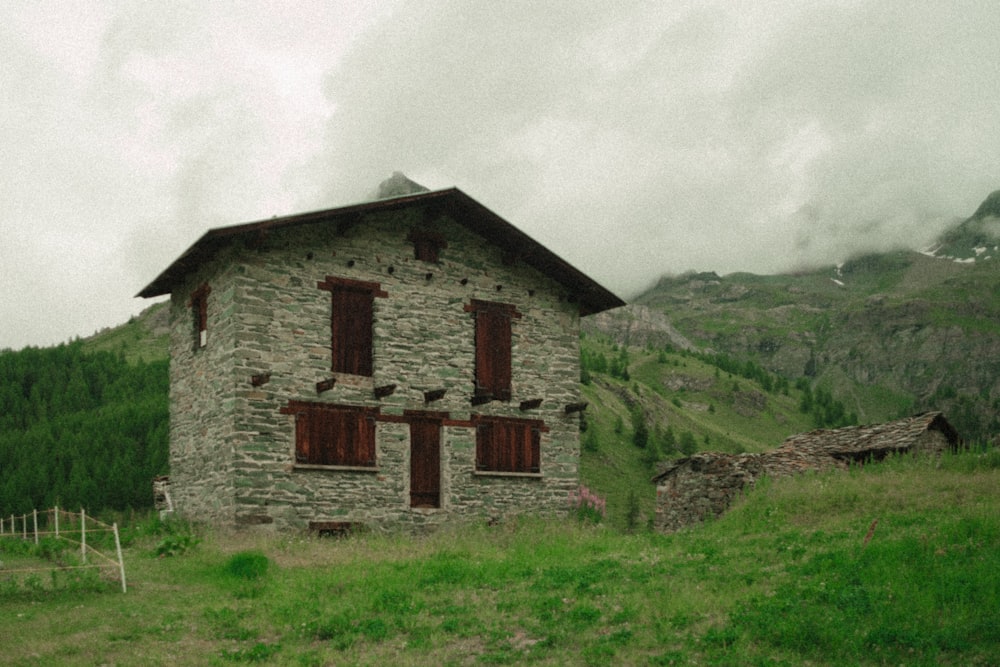 an old stone house in the middle of a grassy field