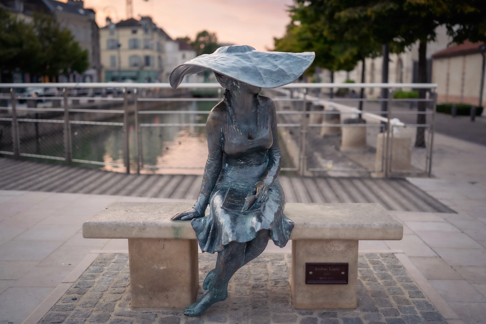 A bronze of a woman on a bench by the water — Troyes, France