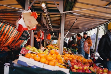 a group of people standing around a fruit stand
