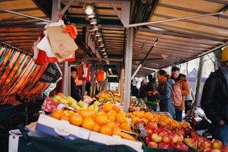 a group of people standing around a fruit stand