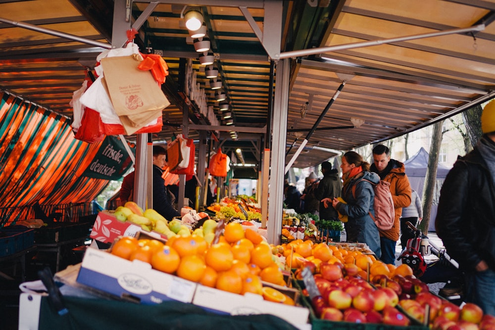 a group of people standing around a fruit stand