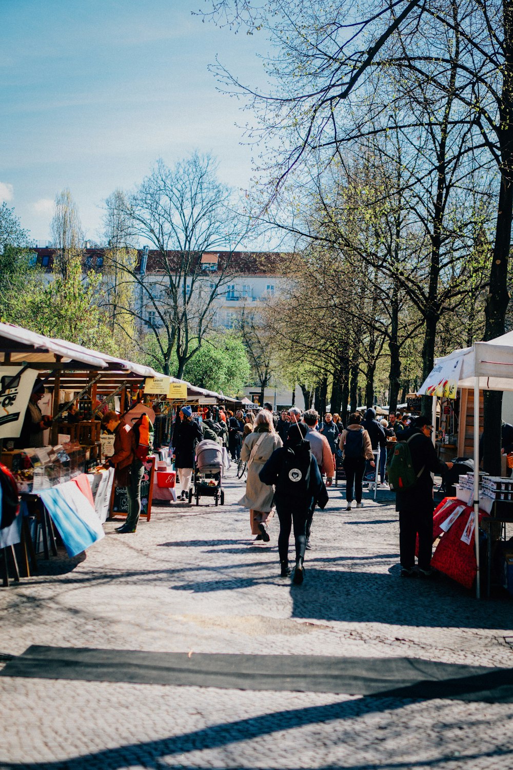 a group of people walking down a street next to tents