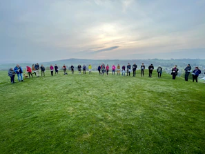 Students gathered in a circle outdoors during a mentorship session under a bright sky