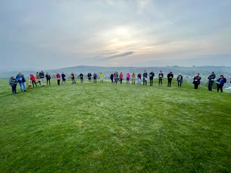 Students gathered in a circle outdoors during a mentorship session under a bright sky