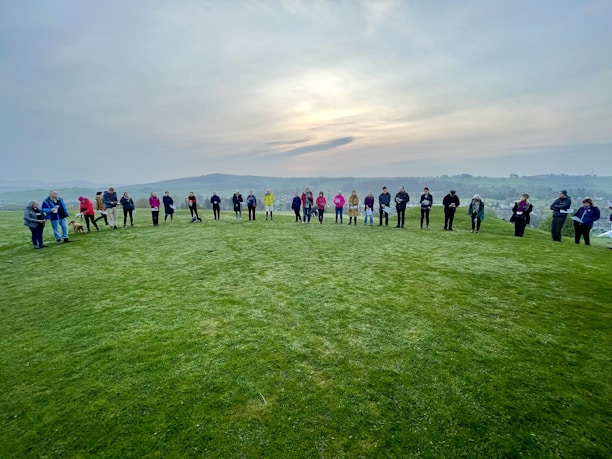 A serene group circle outdoors, people holding hands in support under soft sunlight.