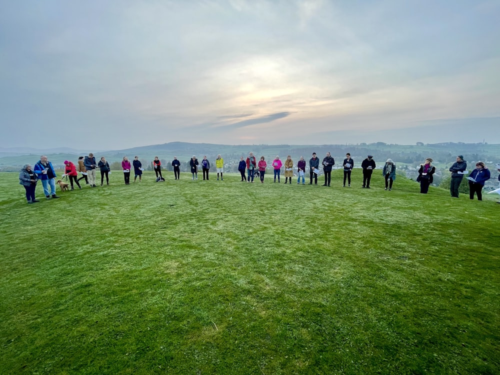 a group of people standing on top of a lush green field