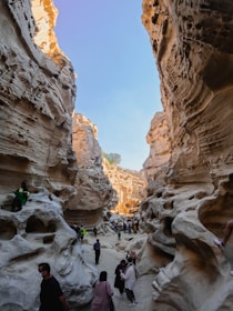 a group of people walking through a narrow canyon