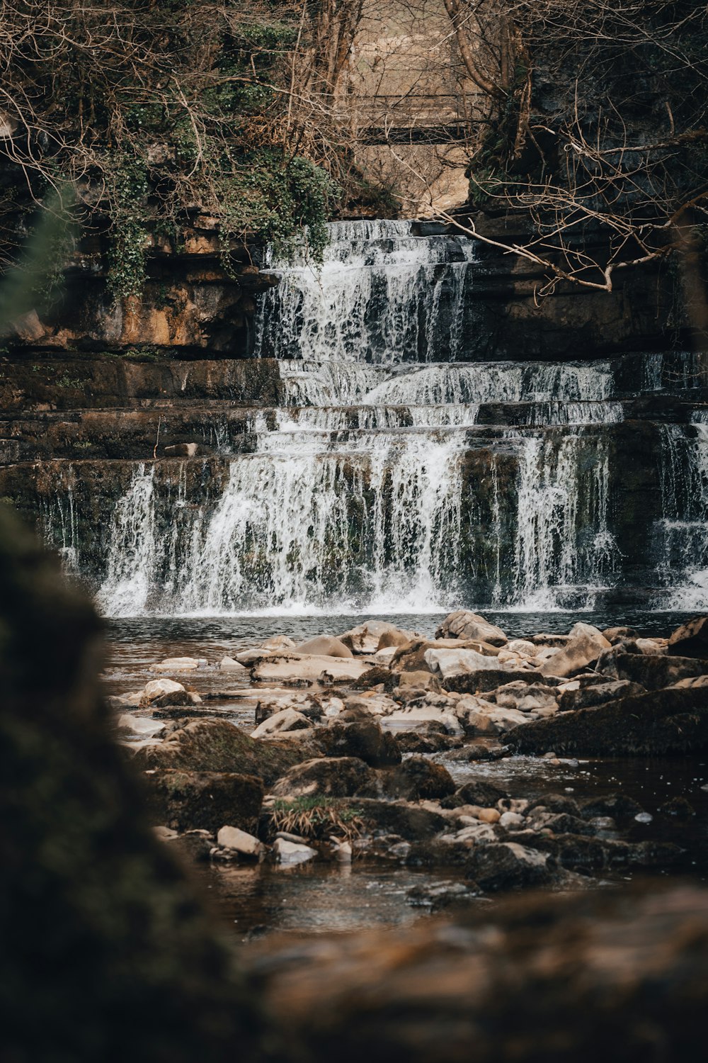 a waterfall with rocks and trees in the foreground