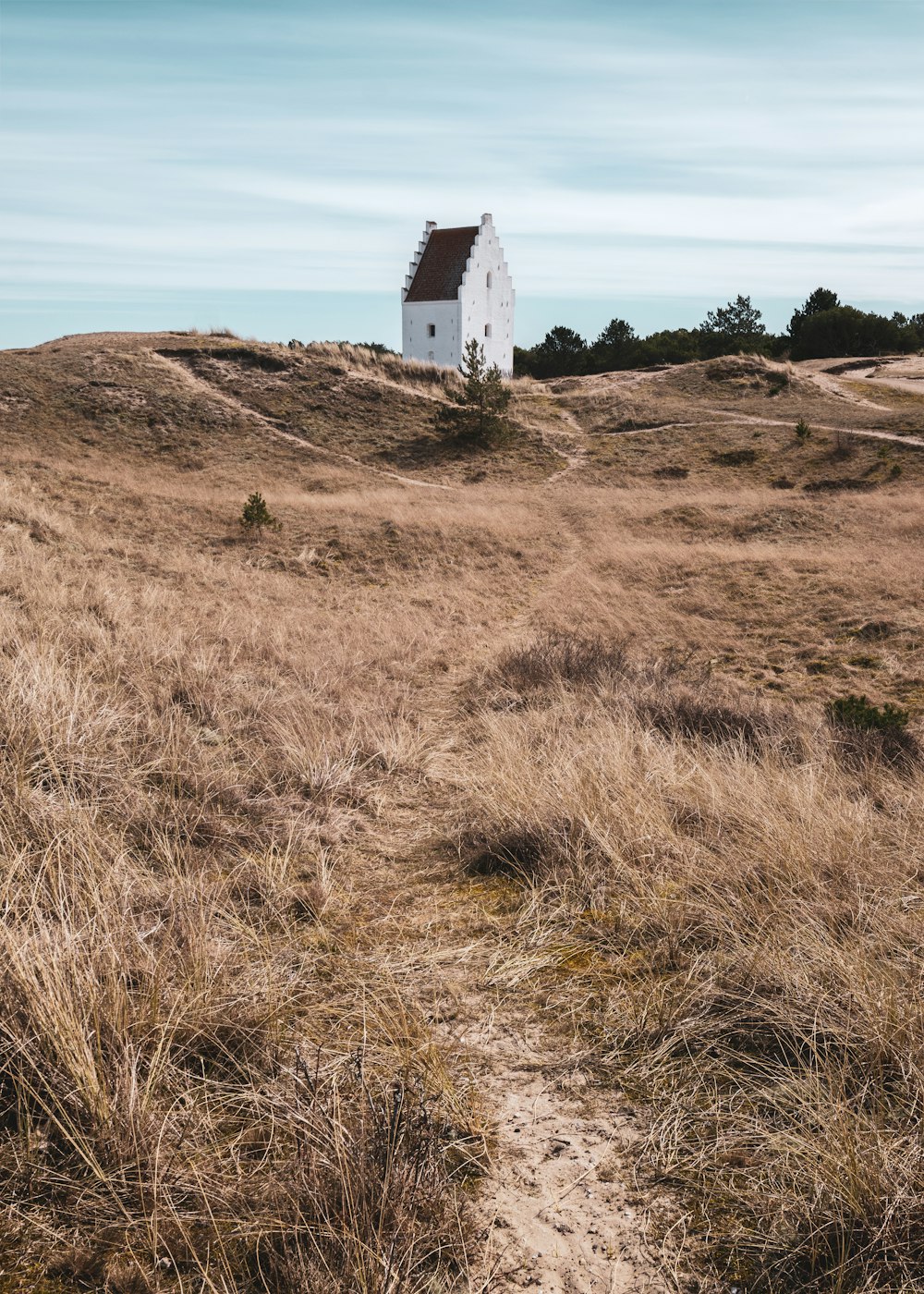 a white house sitting on top of a dry grass covered hill