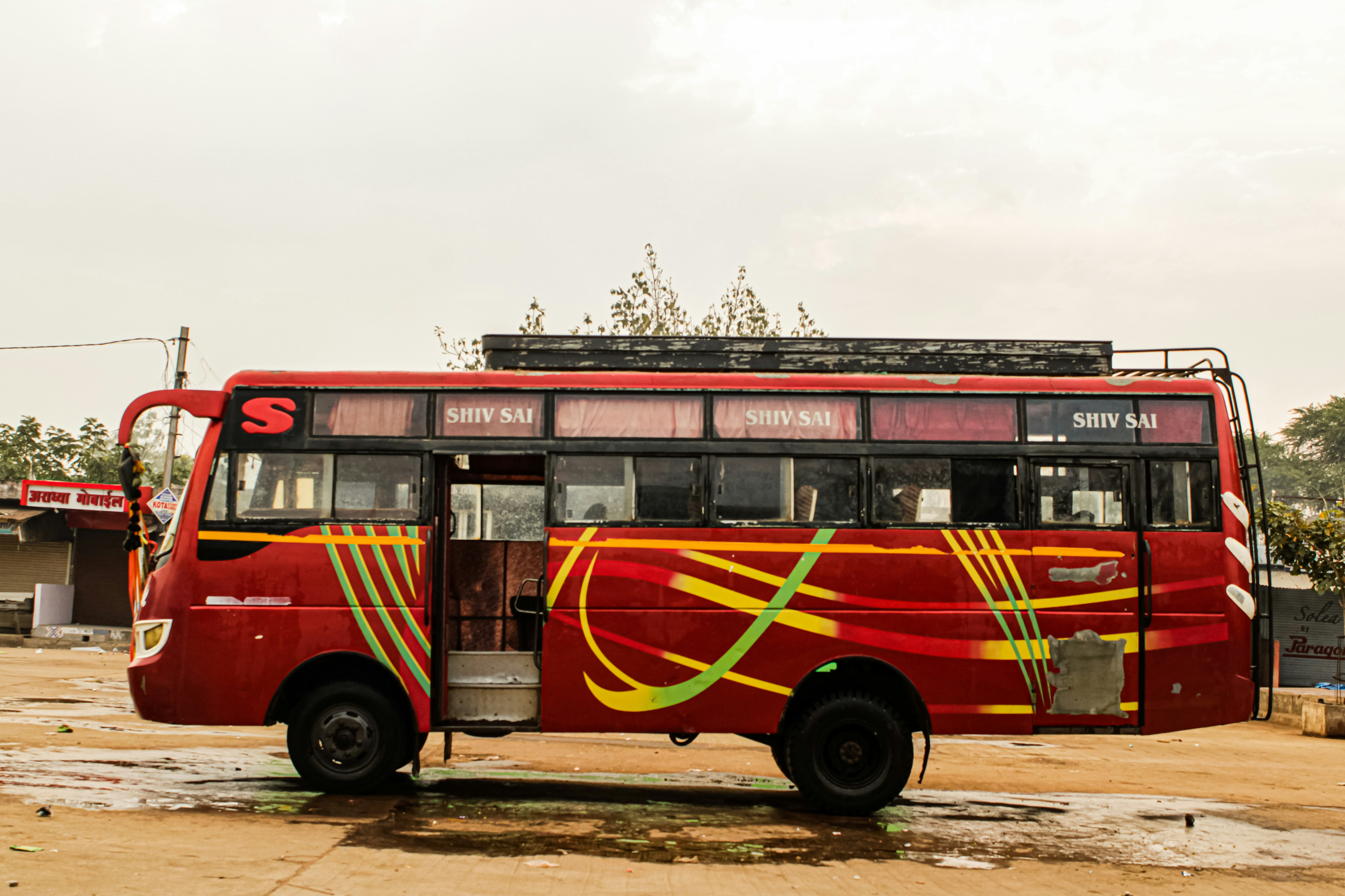 a red bus parked on a dirt road