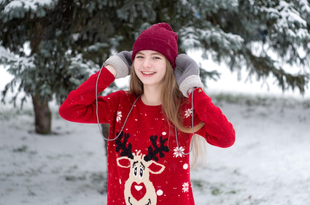 a girl in a red christmas sweater listening to headphones