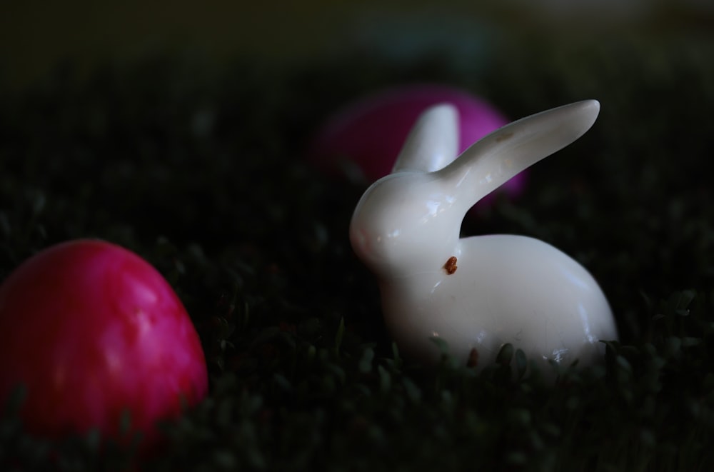 a close up of a white rabbit figurine in the grass