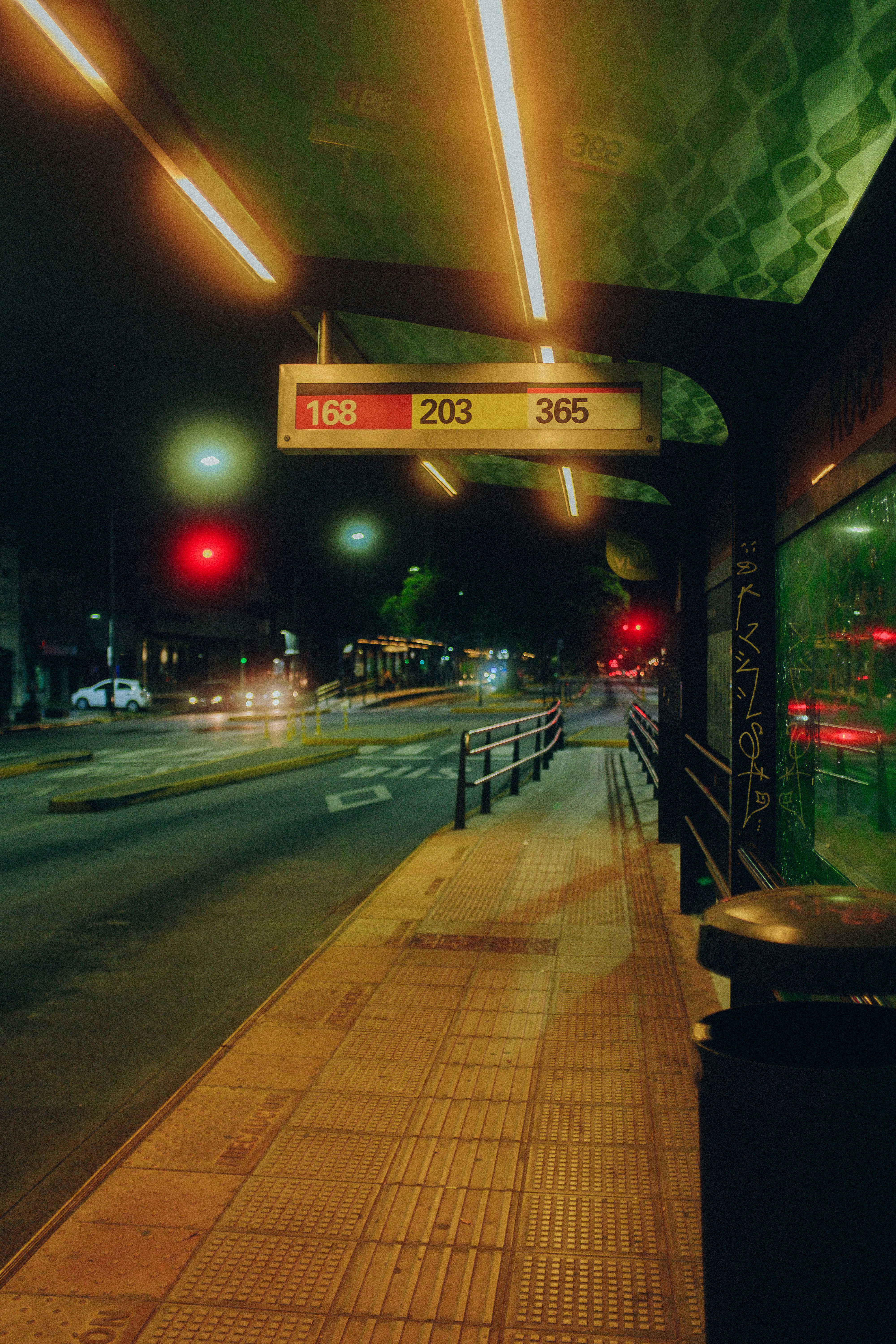 Urban bus stop almost empty at night with neon lights and colored glass in Buenos Aires, Argentina