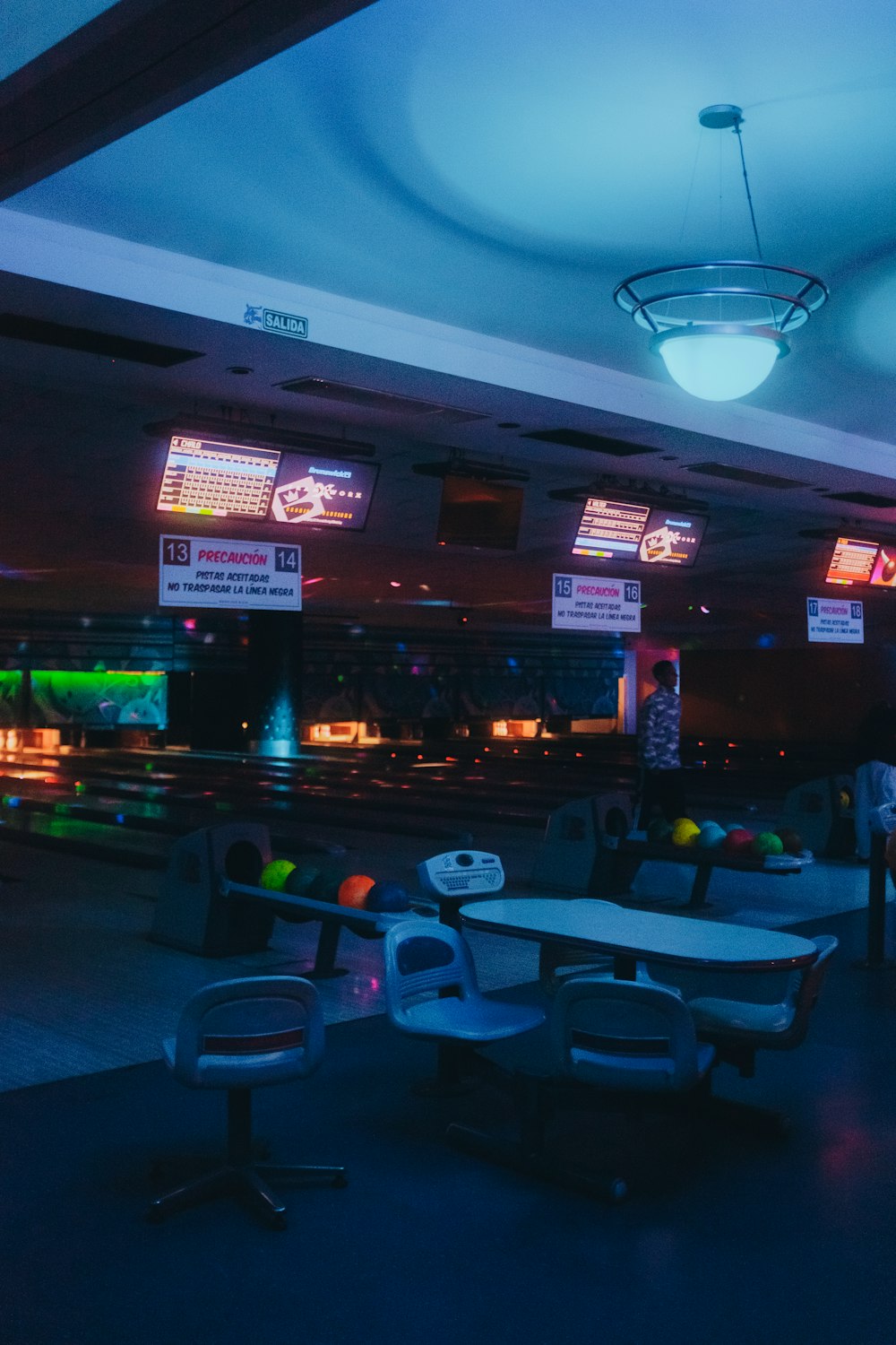 a bowling alley with bowling tables and neon lights