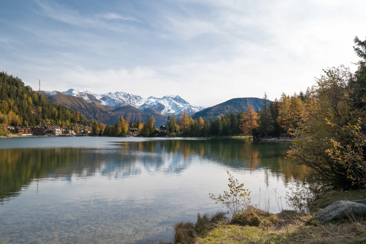 The lake at Champex-Lac in autumn, with trees turning yellow and snowy peaks behind