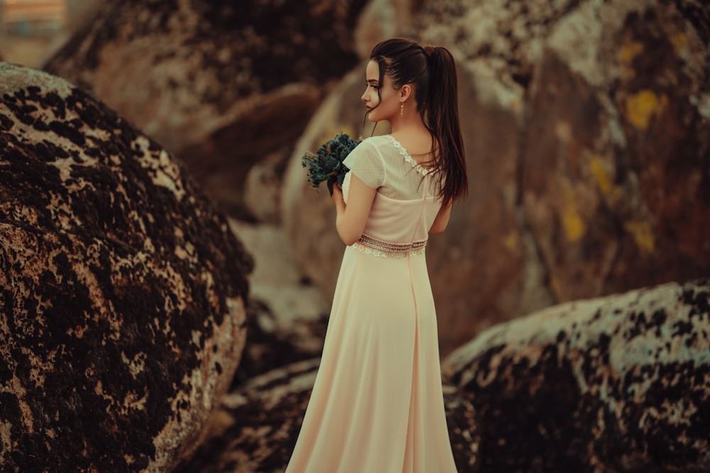 a woman in a long dress holding a bouquet of flowers