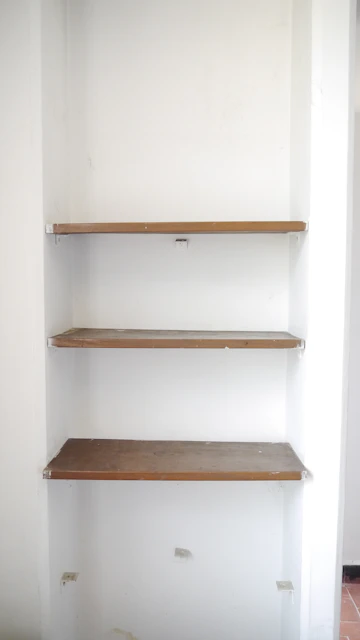 empty shelves in a white room with a tile floor