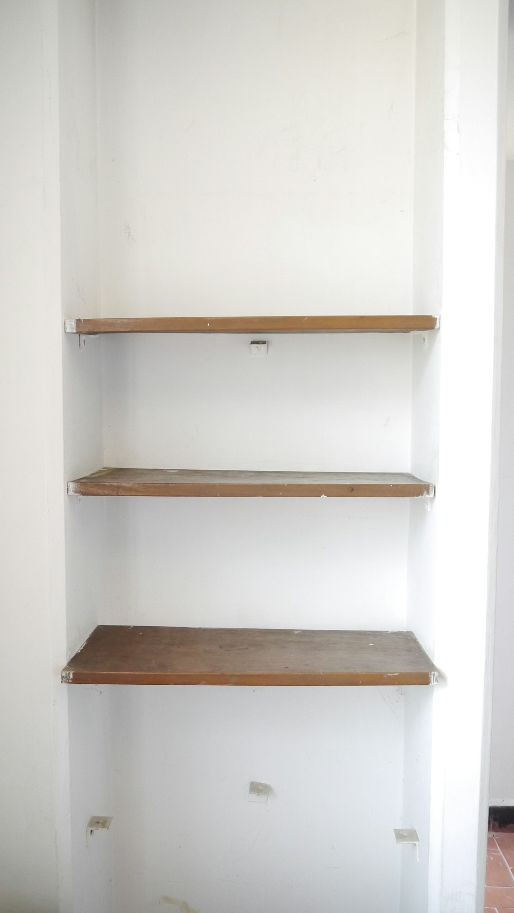 empty shelves in a white room with a tile floor