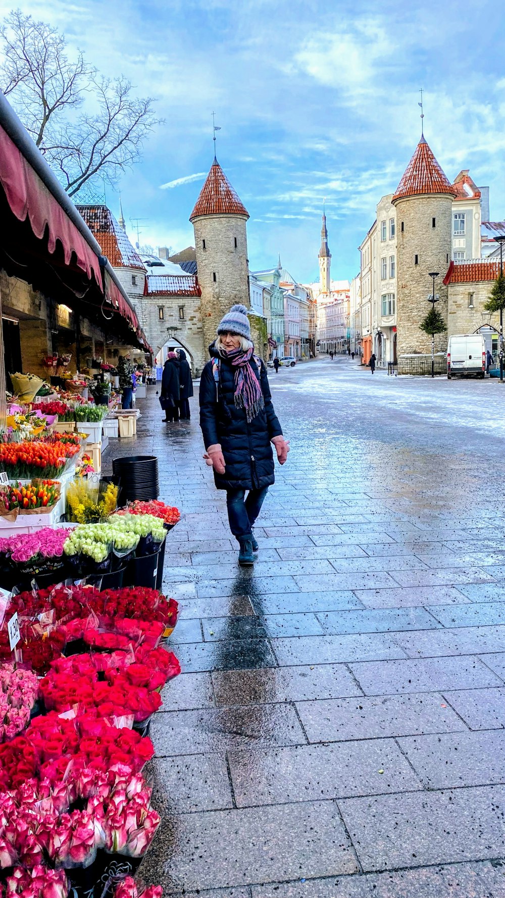 a man walking down a street next to a bunch of flowers