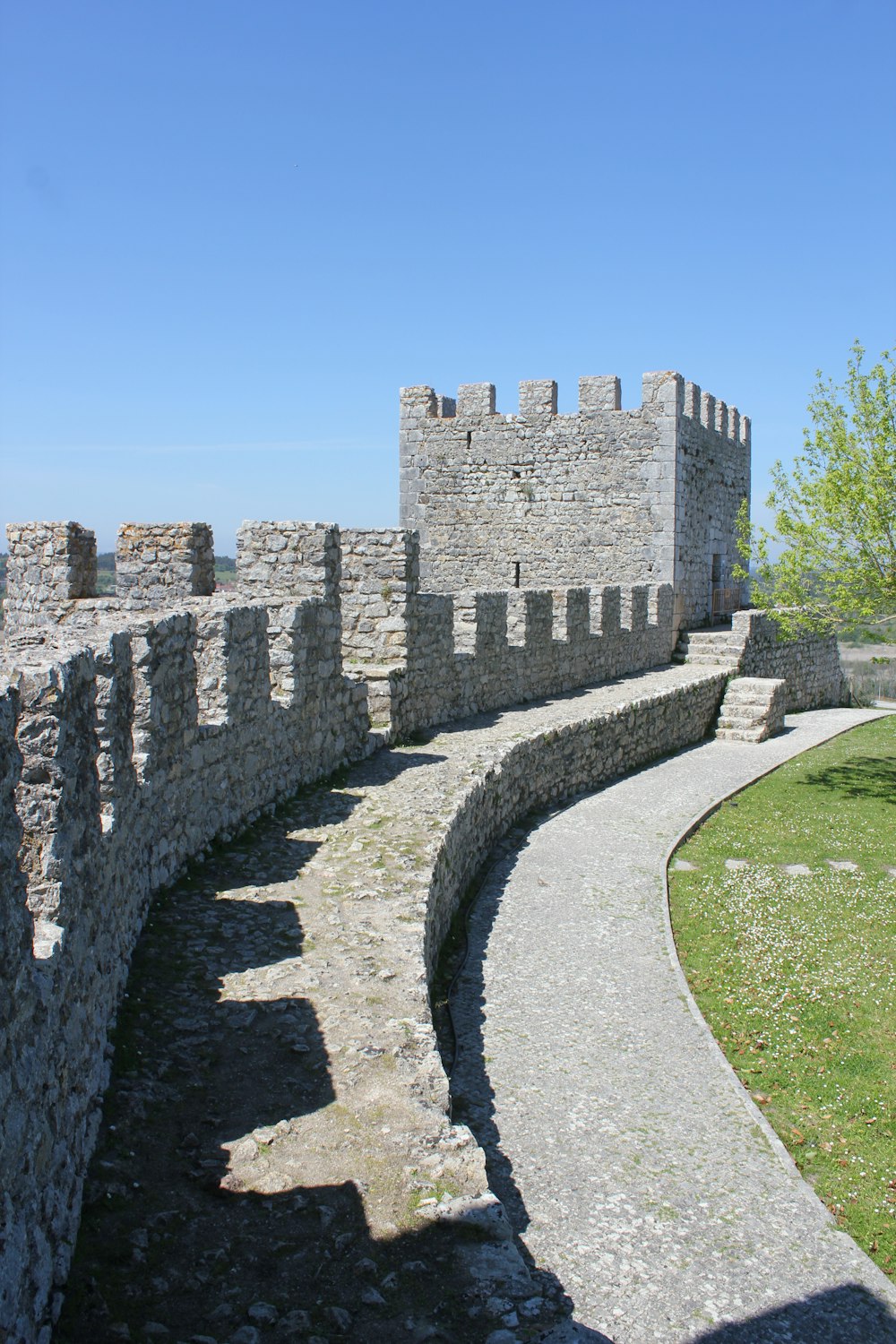 a stone wall and walkway leading to a castle