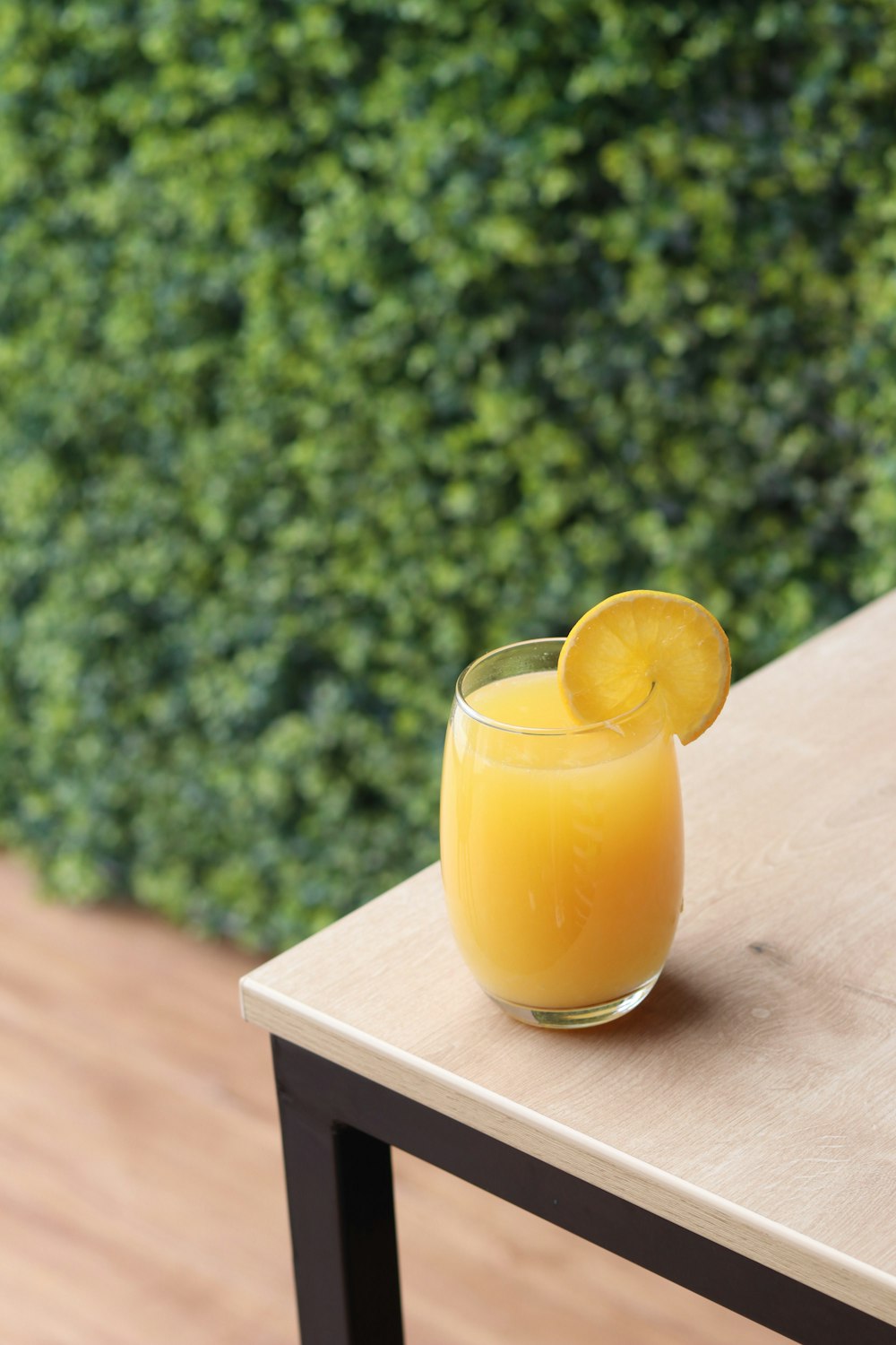 a glass of orange juice sitting on top of a wooden table