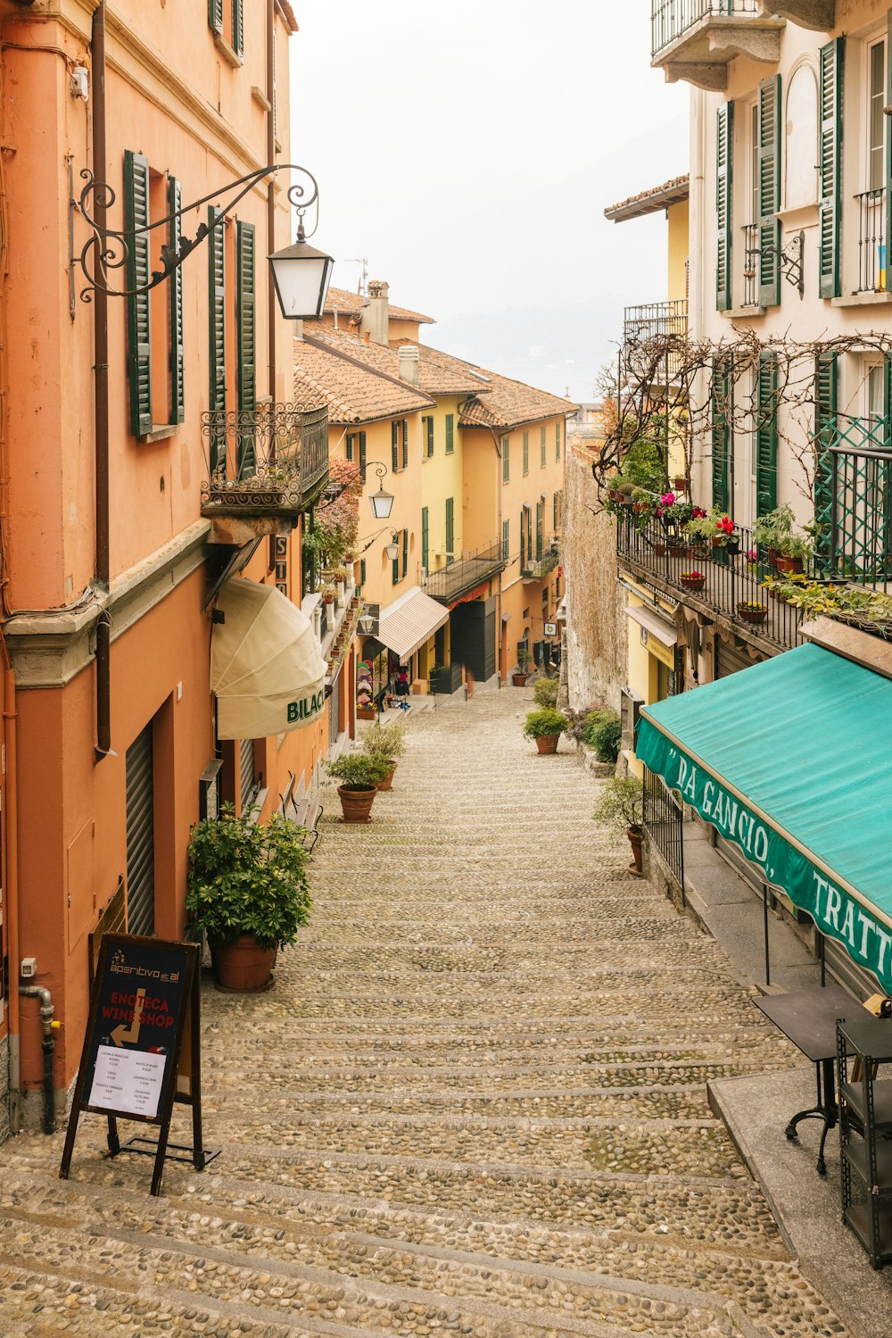 a cobblestone street lined with buildings and tables