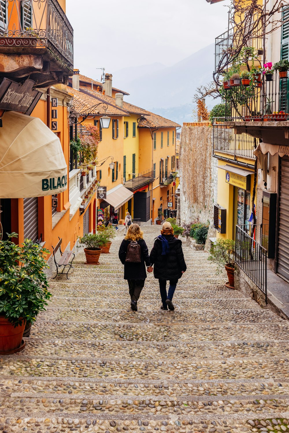 two people walking down a cobblestone street