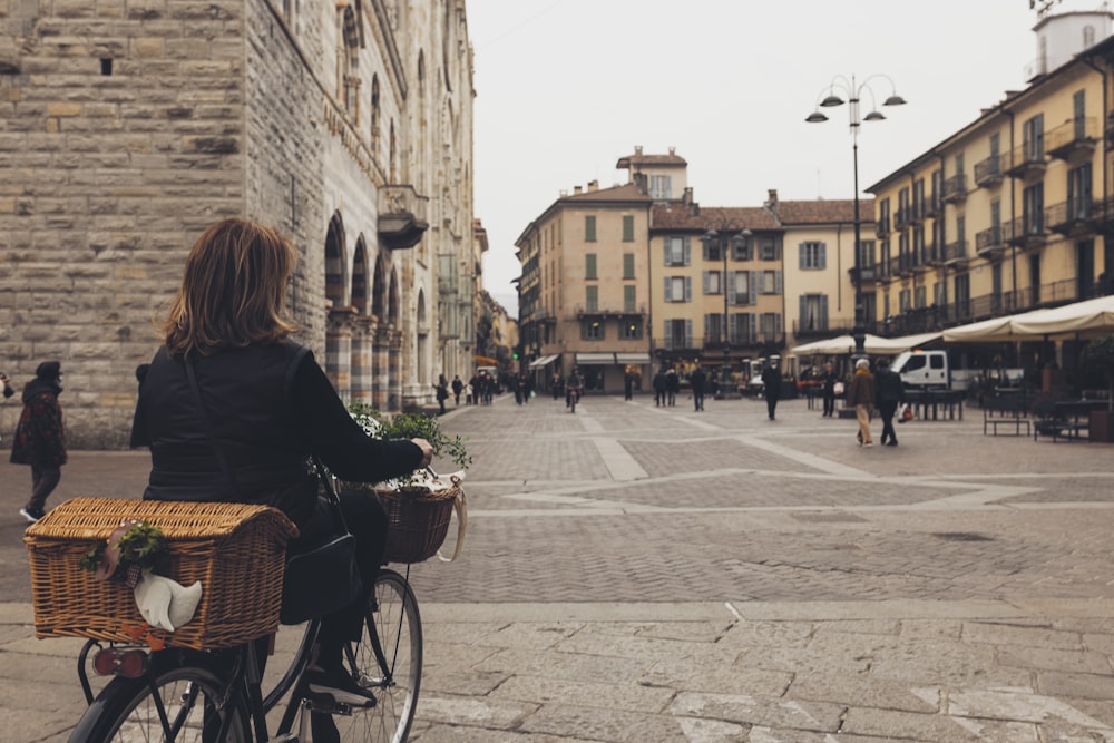 a woman riding a bike down a street next to tall buildings