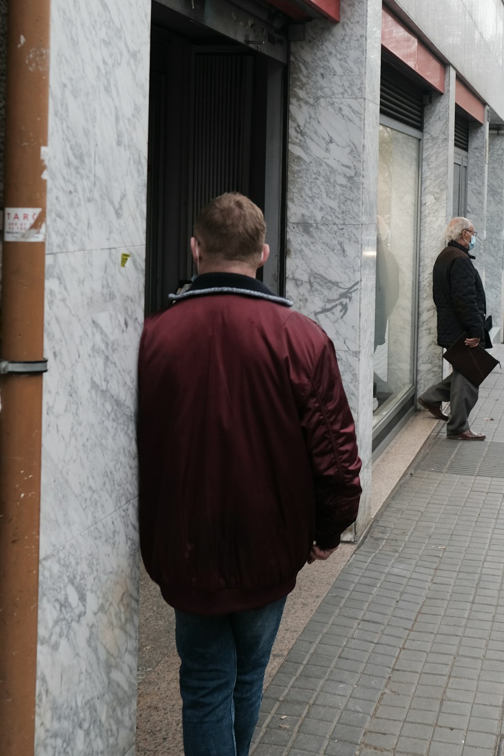 a man walking down a sidewalk next to a tall building