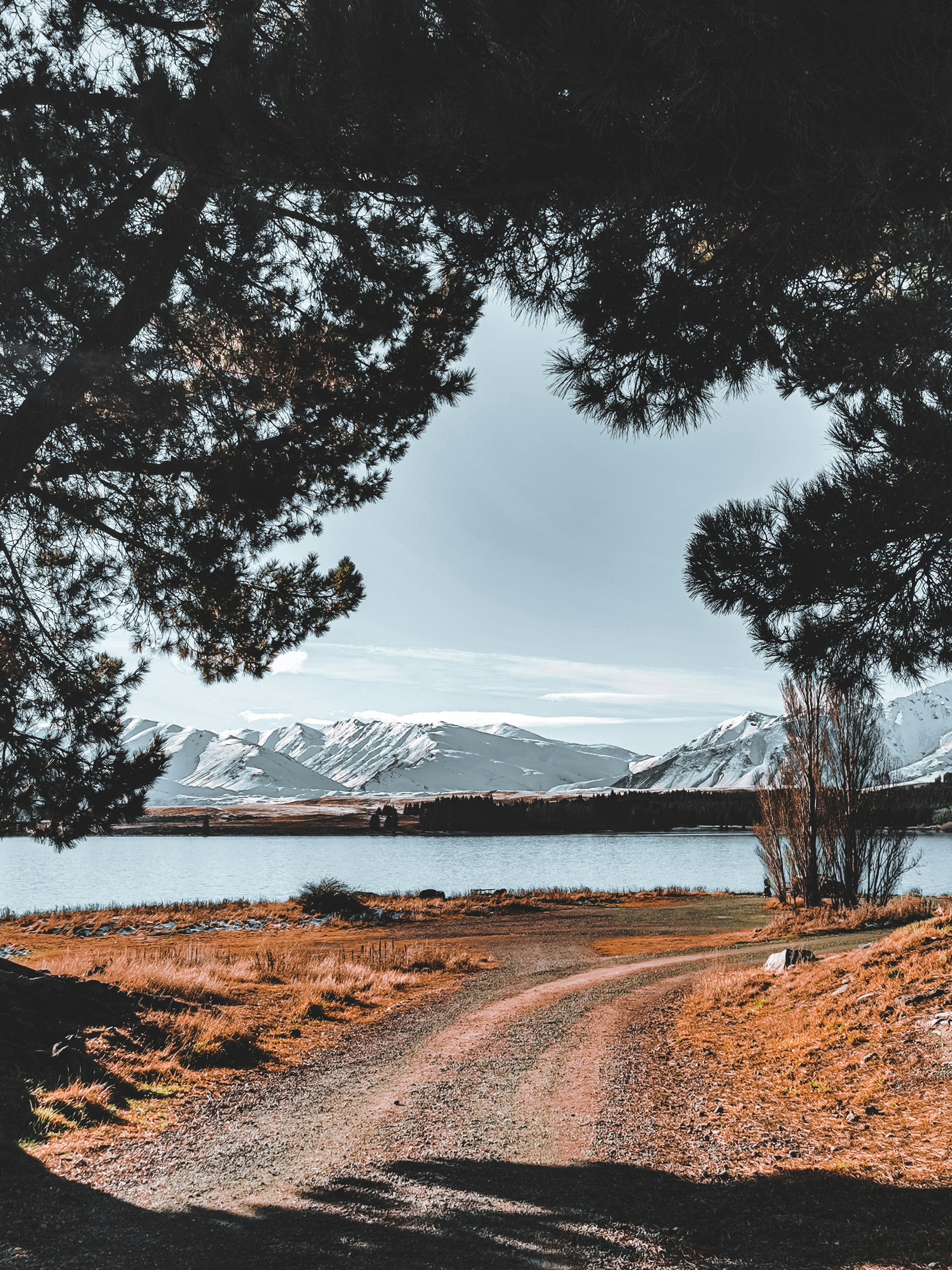 Un camino de tierra con un lago y montañas al fondo foto – Imagen de ...