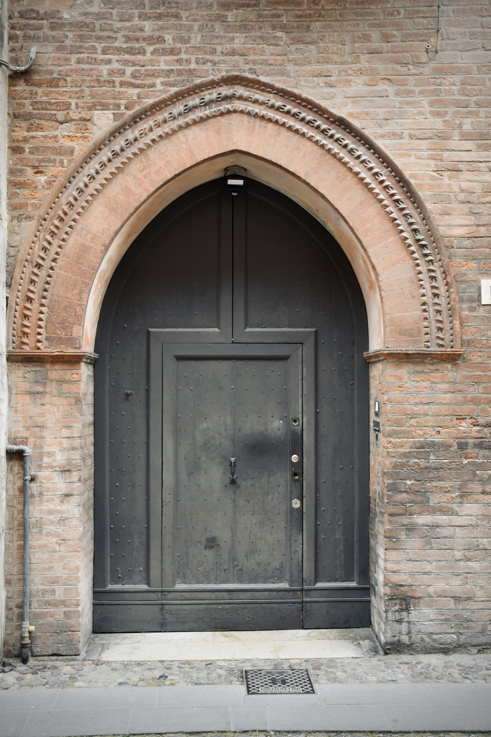 una puerta negra con un arco de ladrillo encima