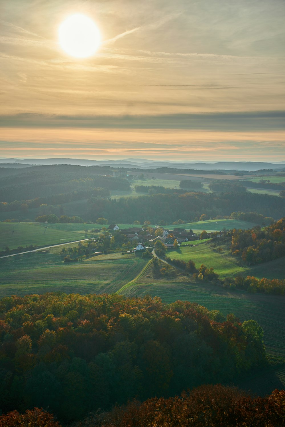 the sun is setting over a green valley