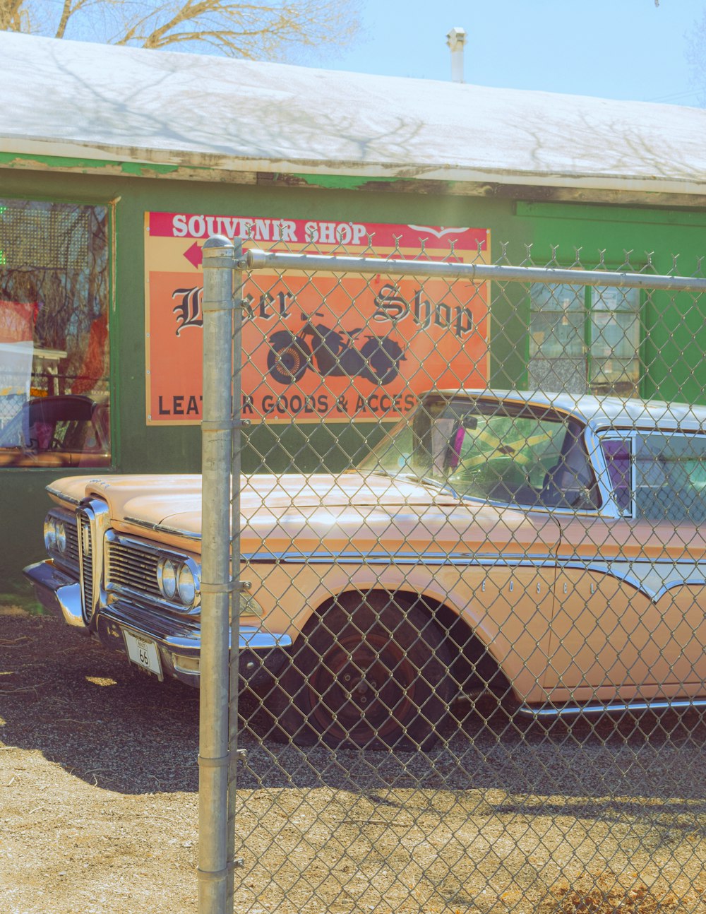 an old car behind a chain link fence