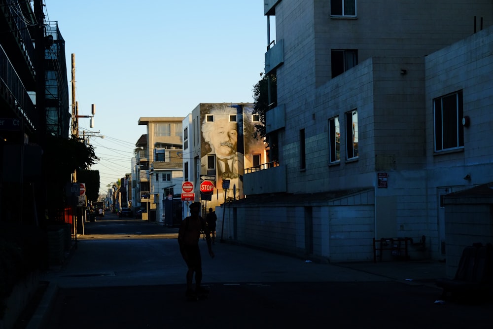 a couple of people walking down a street next to tall buildings