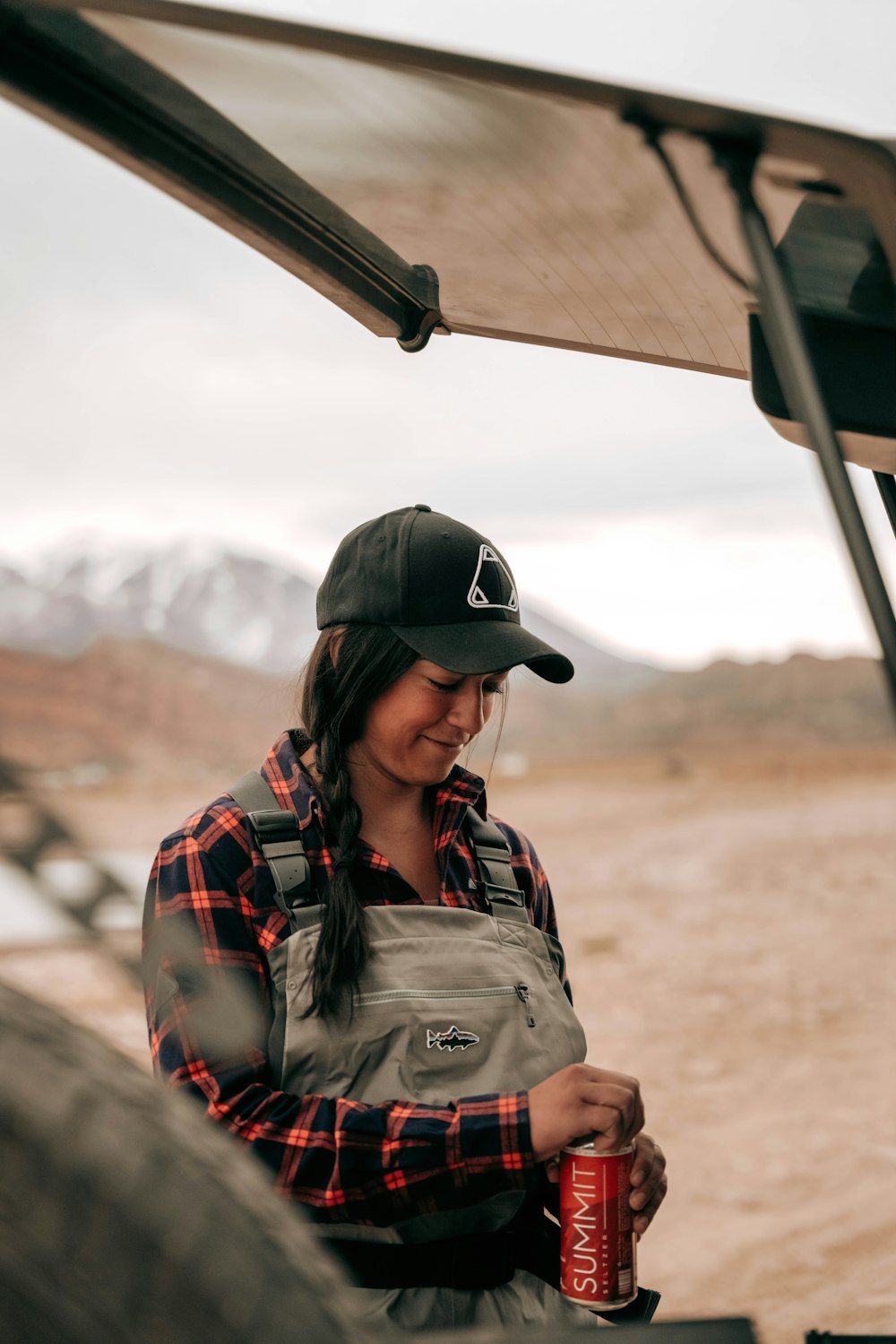 a woman wearing a hat and holding a can of soda