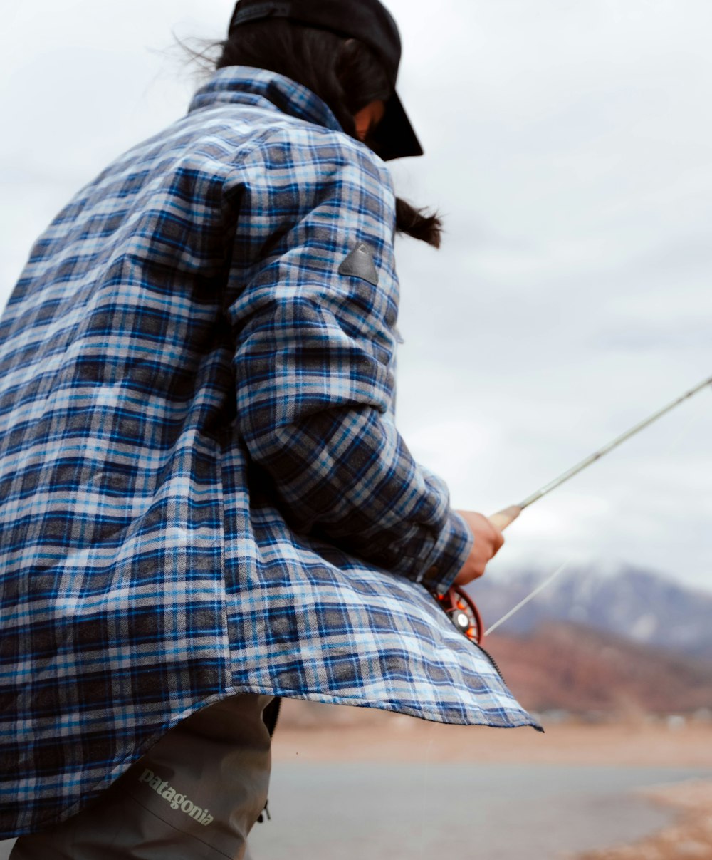 a woman holding a fishing pole while standing next to a lake