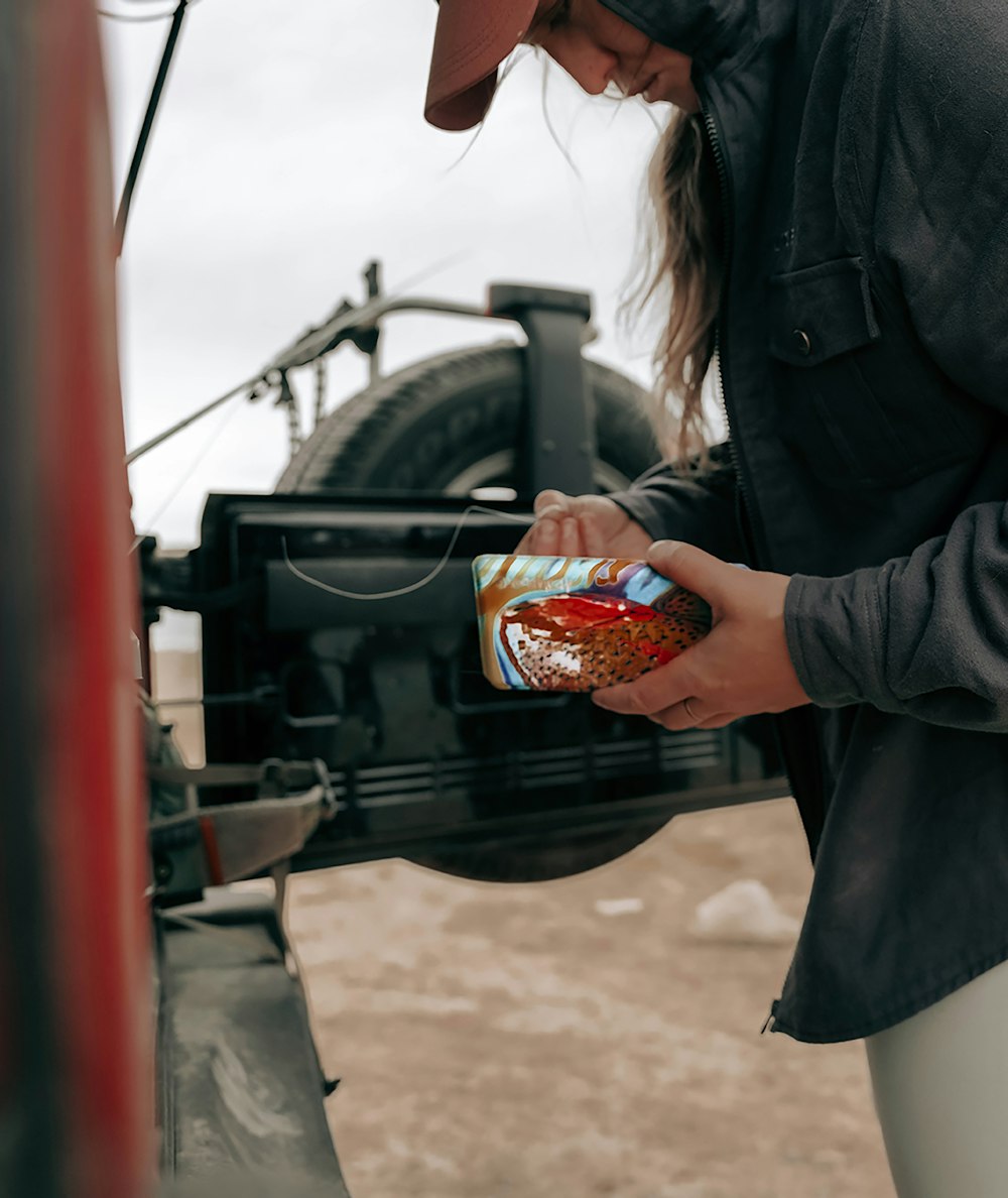 a man standing next to a truck holding a can of food