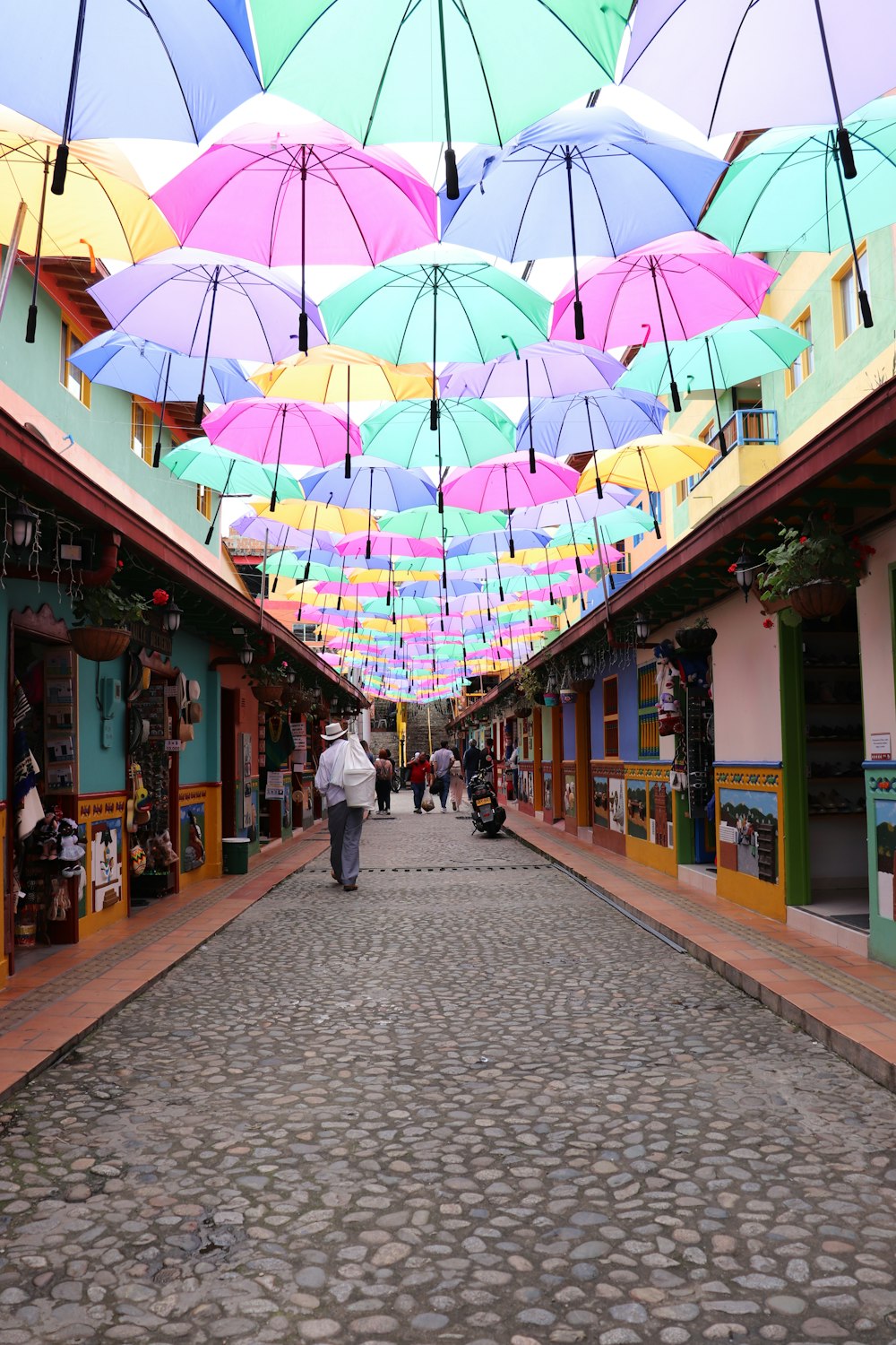 a group of people walking down a street under umbrellas