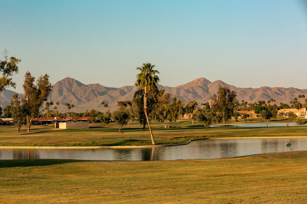 a golf course with a lake and mountains in the background