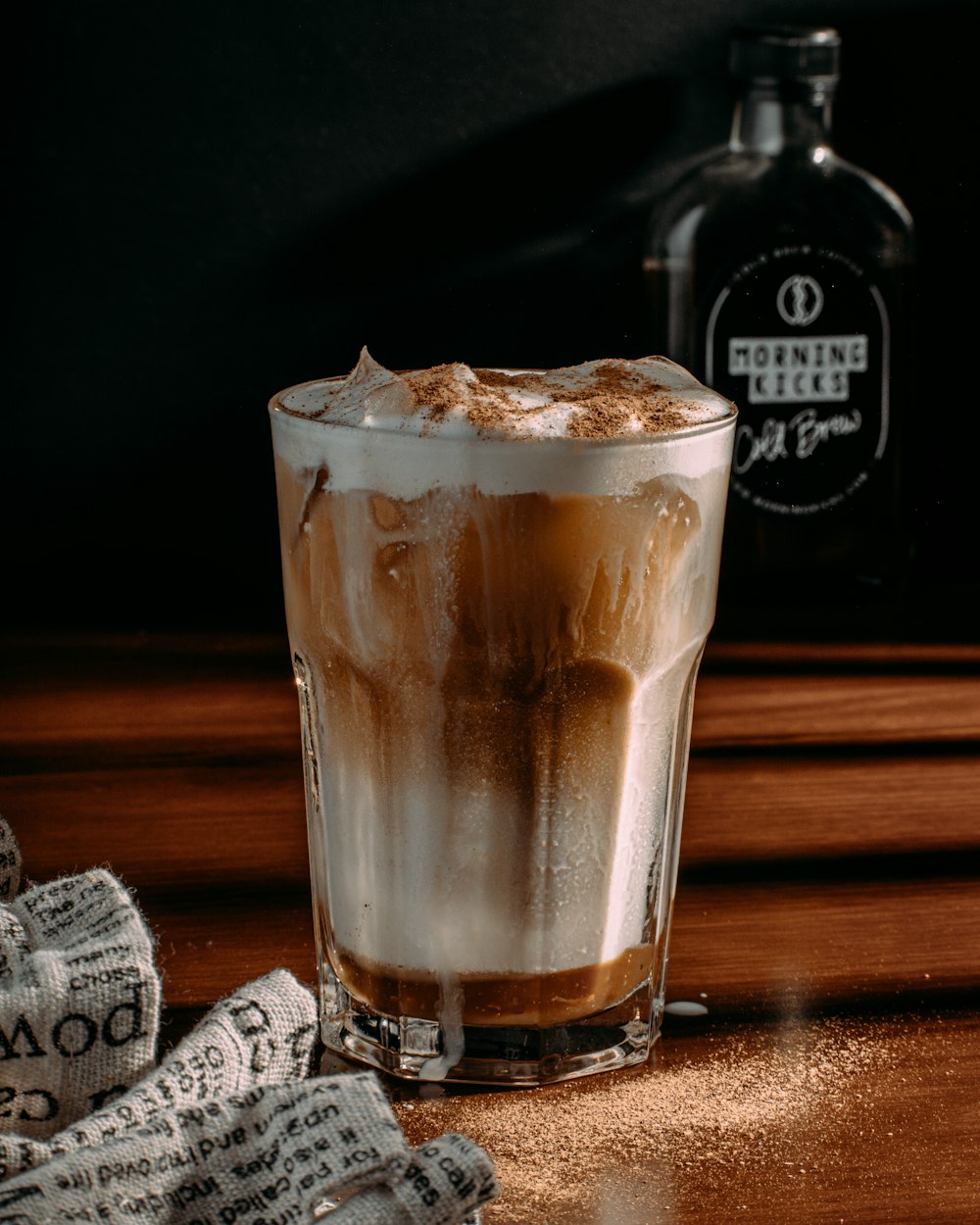 a glass of iced coffee sitting on top of a wooden table