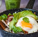 a bowl of food with an egg, avocado and rice