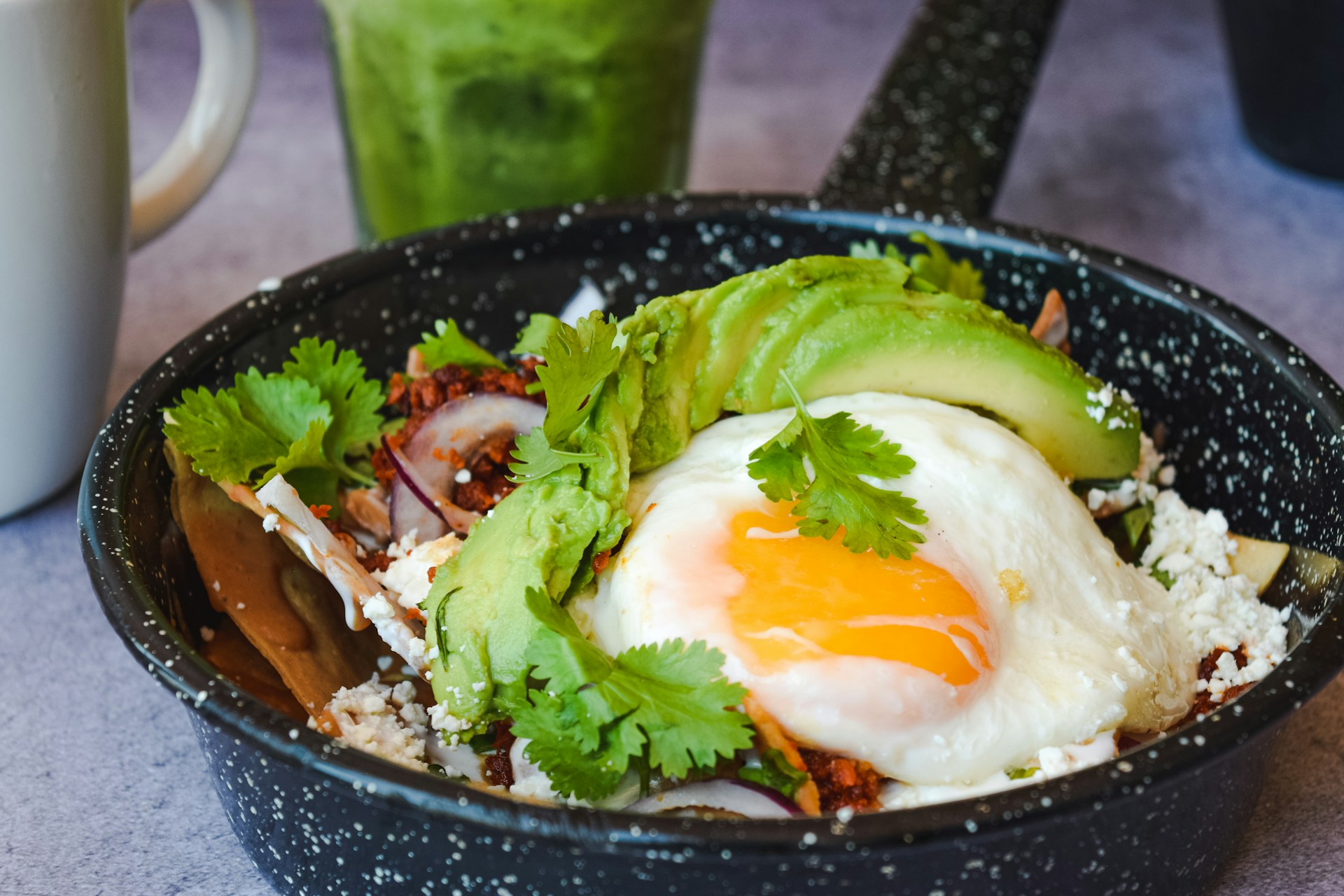 a bowl of food with an egg, avocado and rice