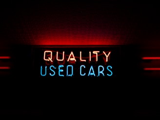 a neon sign that reads quality used cars