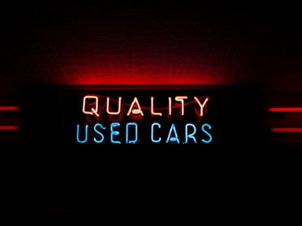 a neon sign that reads quality used cars