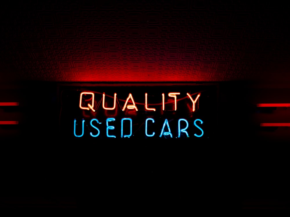a neon sign that reads quality used cars