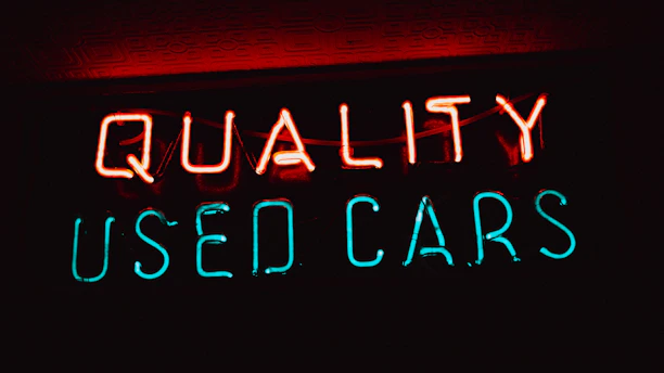 a neon sign that says quality used cars