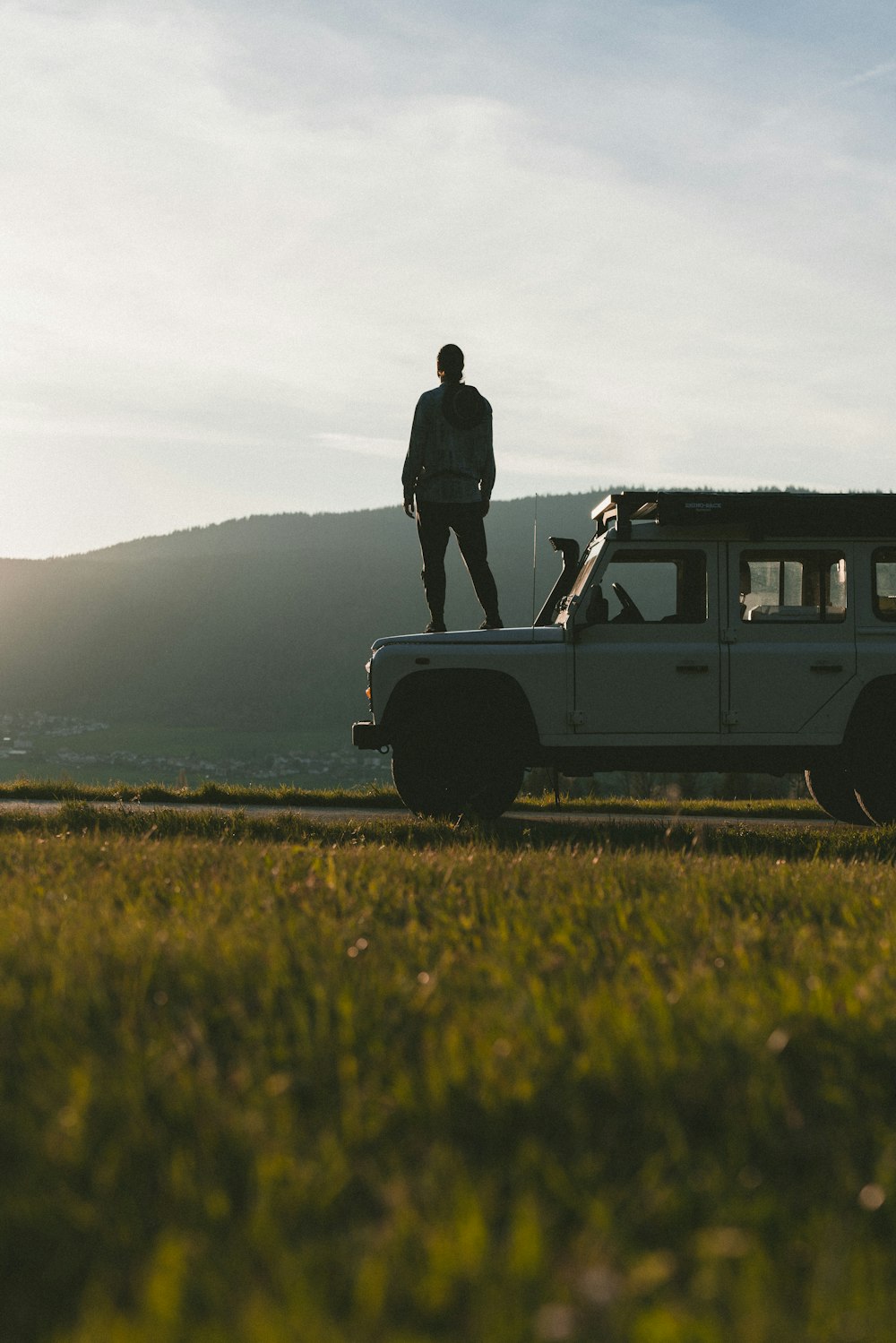 a man standing on top of a jeep in a field