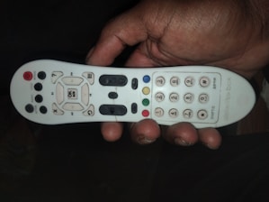 Close-up of hands holding different types of remote controls, showcasing variety and detail.